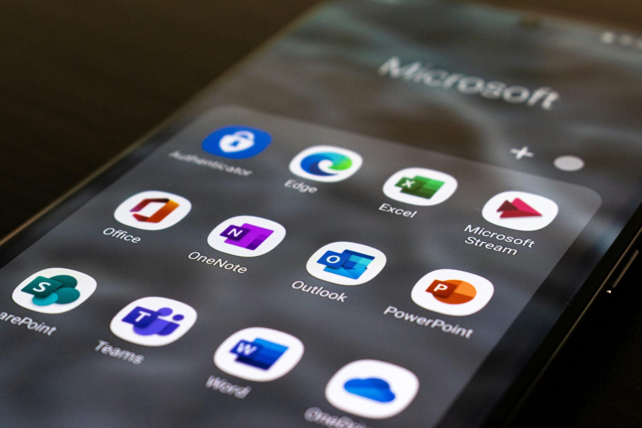 A close up of a mobile phone screen showing several commonly used Microsoft applications including OneDrive.