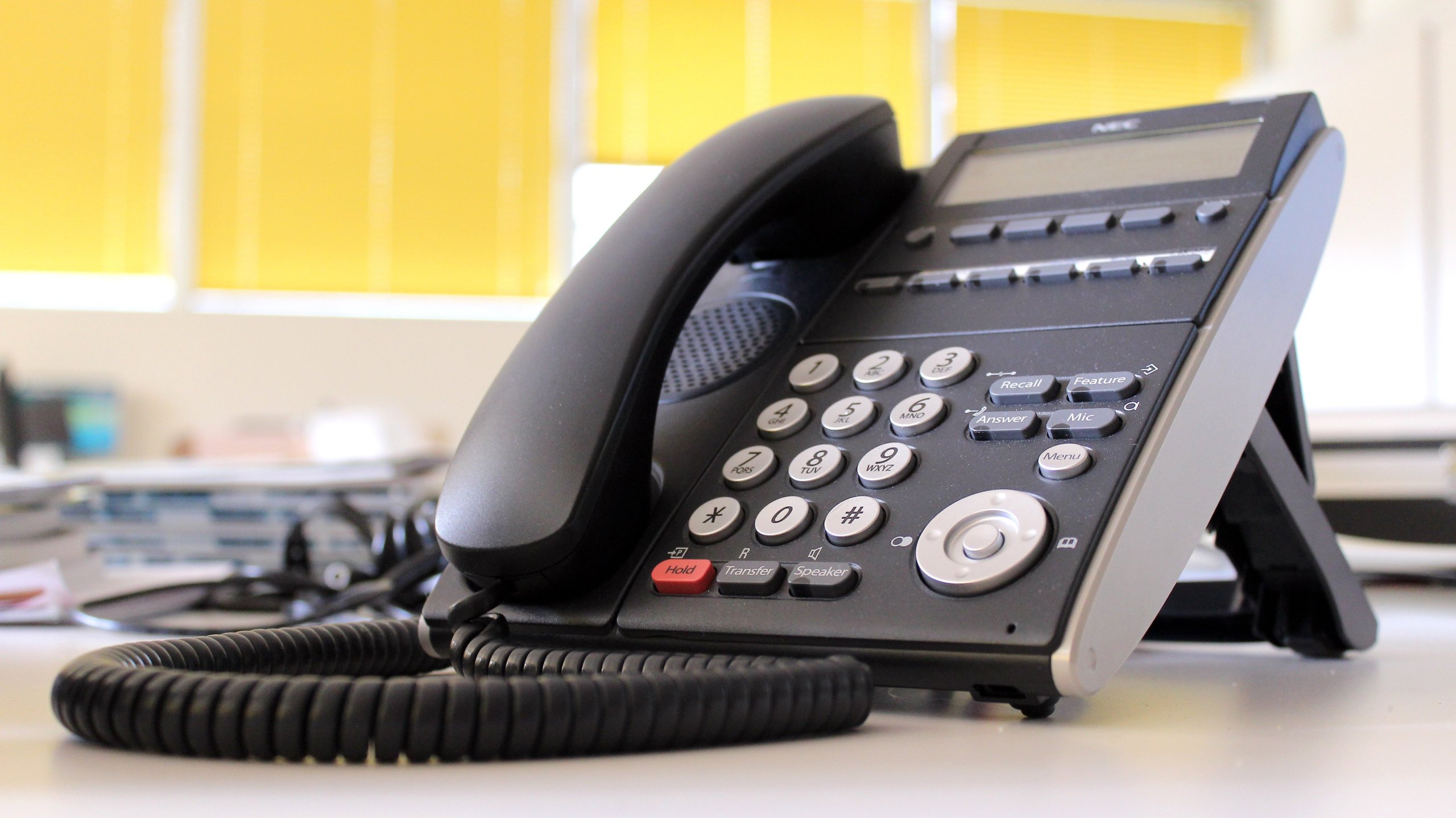 A close up of a business landline phone on a desk.